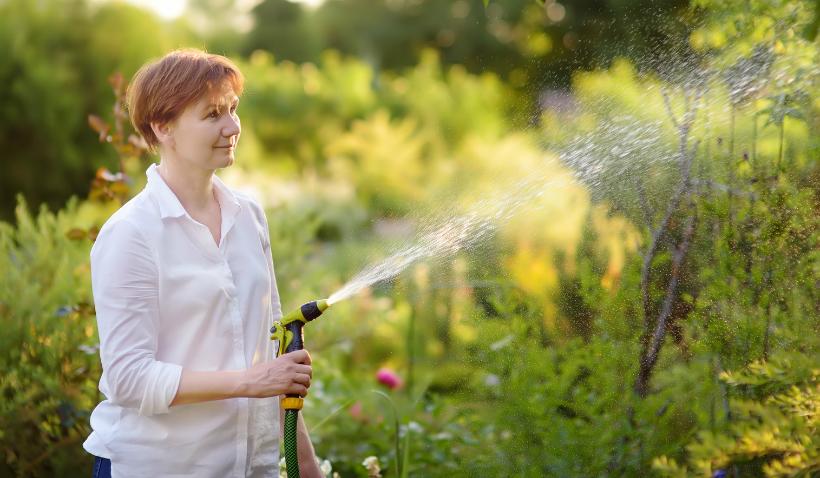 Frau gießt einen Baum im Garten
