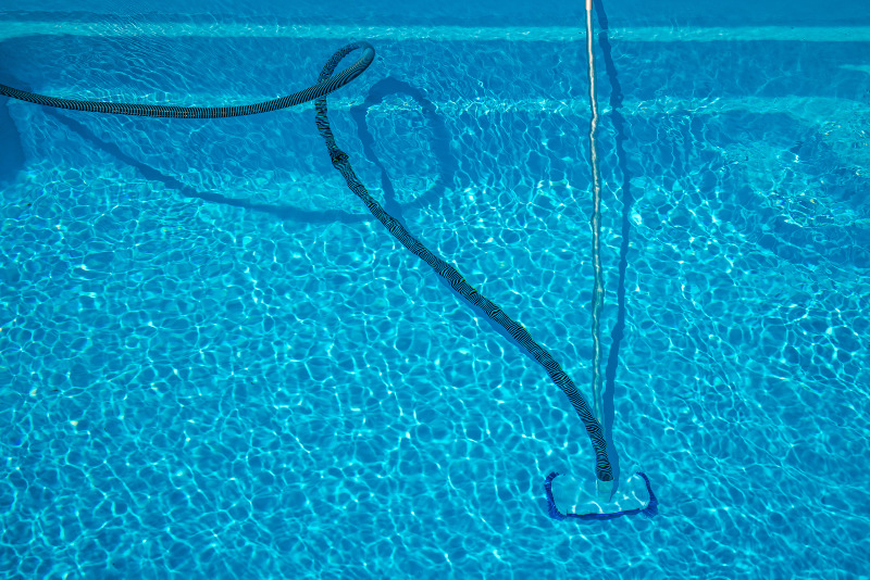 AUch bei der Reinigung des Beckenbodens kommen Poolschläuche zum Einsatz Ein Poolschlauch an einer Reinigungsvorrichtung an einem Pool