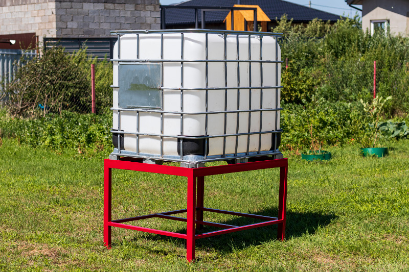 Auch im GArten ist der IBC als Frischwassertank eine praktische Lösung Auf einem Untergestell steht ein IBC in einem Garten
