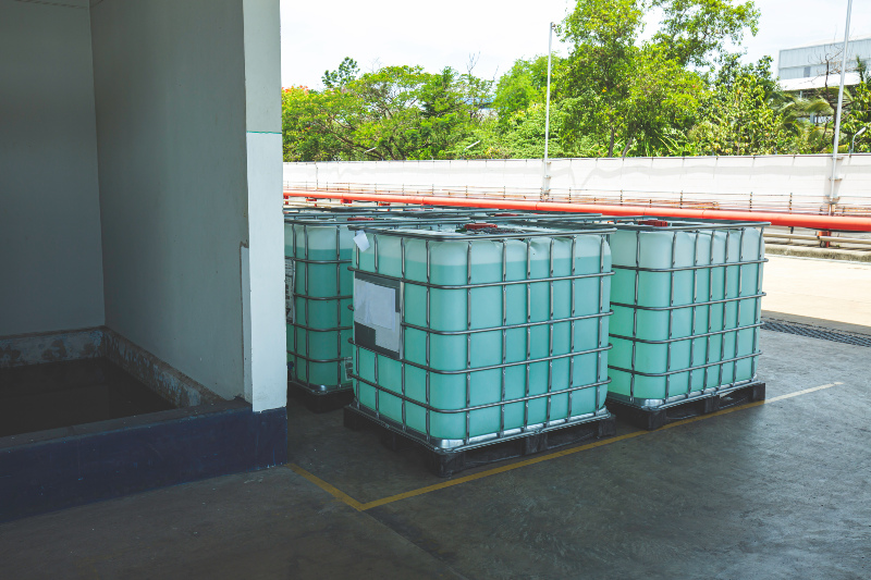 Mehrere IBC Container mit Chemikalien stehen vor einem Lagerhaus 