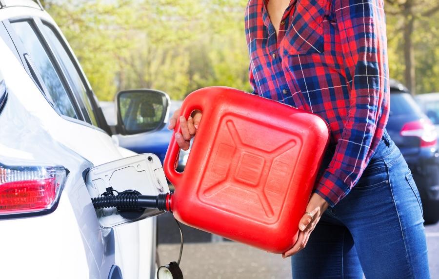 Frau mit Plastikkanister fuellt den Autotank