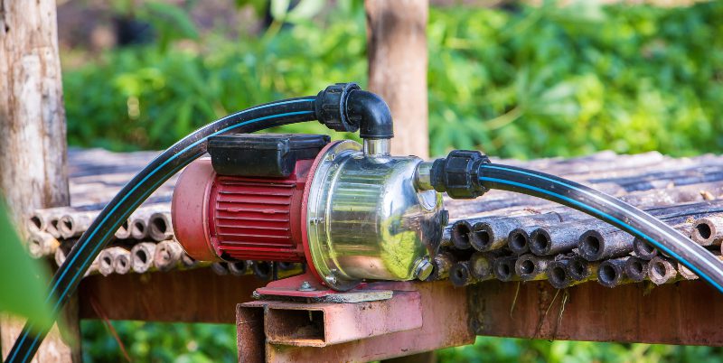 Wasserpumpe Pumpen von Wasser aus dem Garten während der Flut durch die  großen roten Schlauch über draht zaun Stockfotografie - Alamy