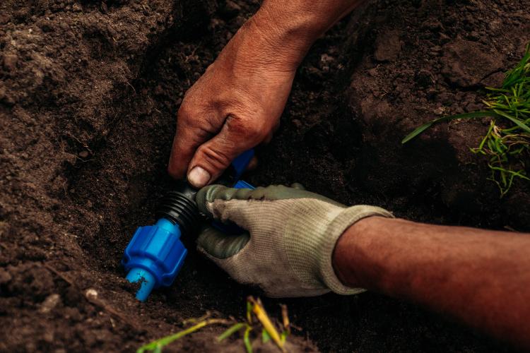 Mann installiert Bewässerungsleitungen im Boden