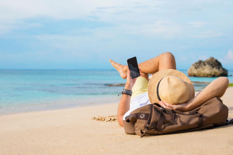 Mann mit Handy am Strand