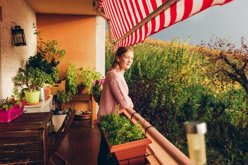 Frau auf einem Balkon mit Pflanzen