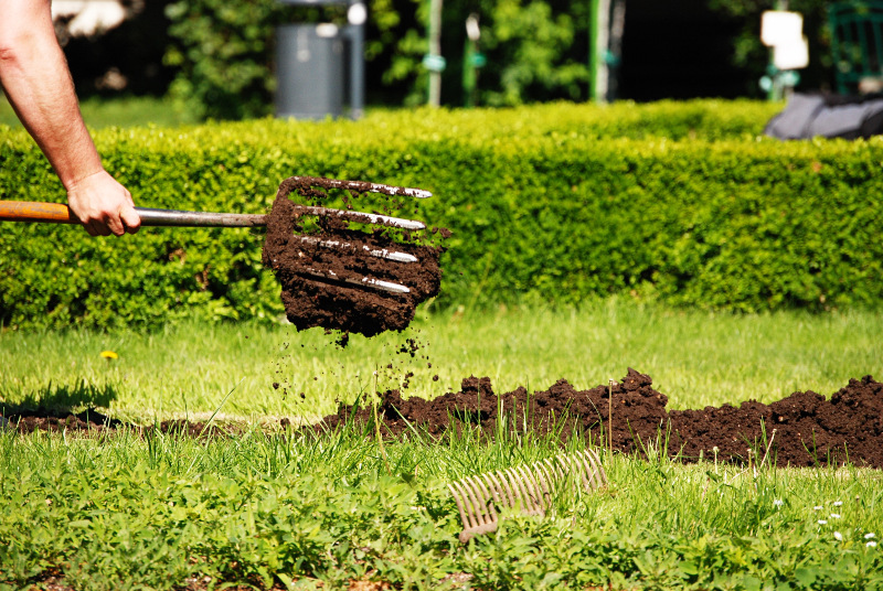 Das Umgraben vor dem Anlegen ist etwas anstrengen, lohnt sich aber Auf einer Wiese in einem Garten wird der Boden umgegraben, um ein Beet anzulegen