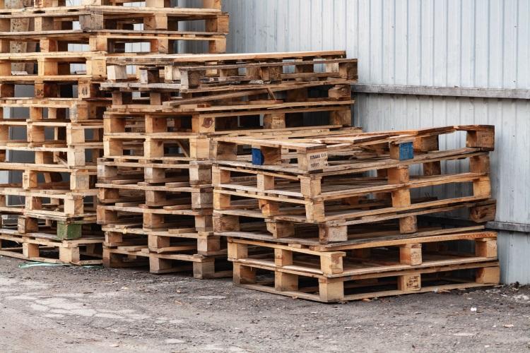 Ein Stapel beschädigter Holzpaletten - Feuchtigkeit und die Belastungen durch den Transport fordern ihren Tribut Containerpaletten aus Kunststoff