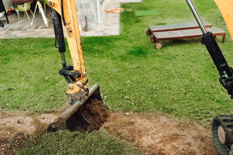 Mit einem kleinen Bagger werden Erdarbeiten in einem Garten vorgenommen Füllstandsmessung des Wassertanks