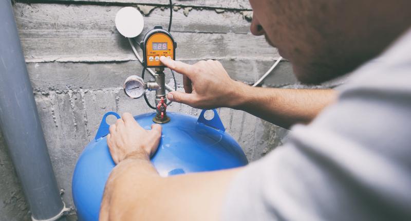 Ein Mann liest an einem elektrischen Anzeigegerät den Füllstand einer Zisterne ab Füllstandsmessung des Wassertanks