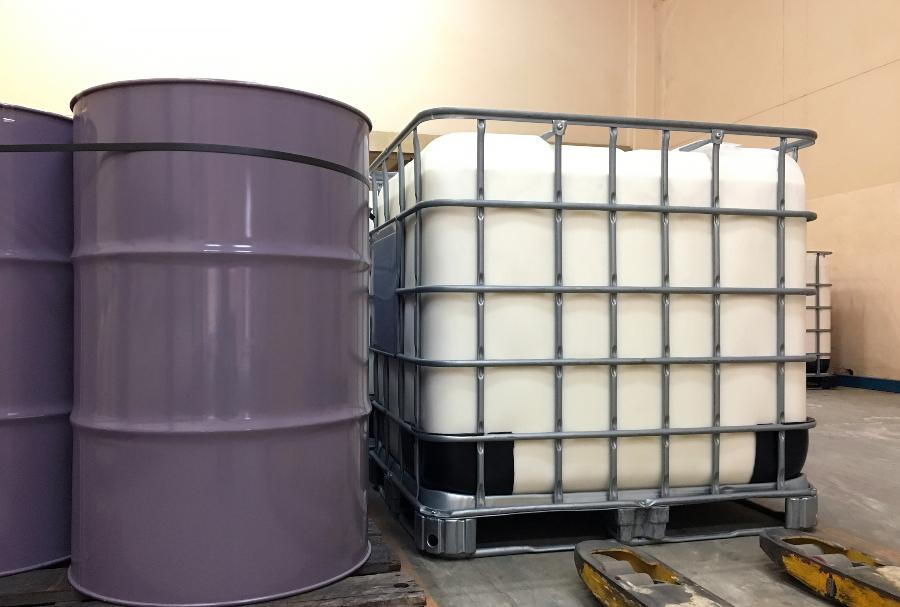 Metallfässer stehen neben einem IBC Container - Vorteile einer Fassbodenheizung