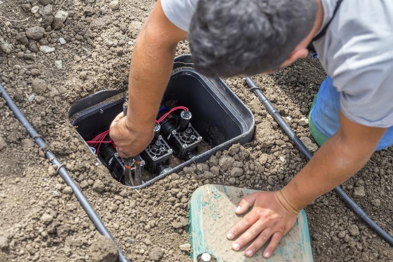 Ein Gärtner montiert Elektroventile in einer Verteilerbox