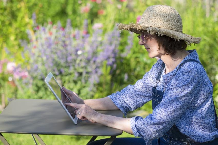 Frau im Garten mit Tablet