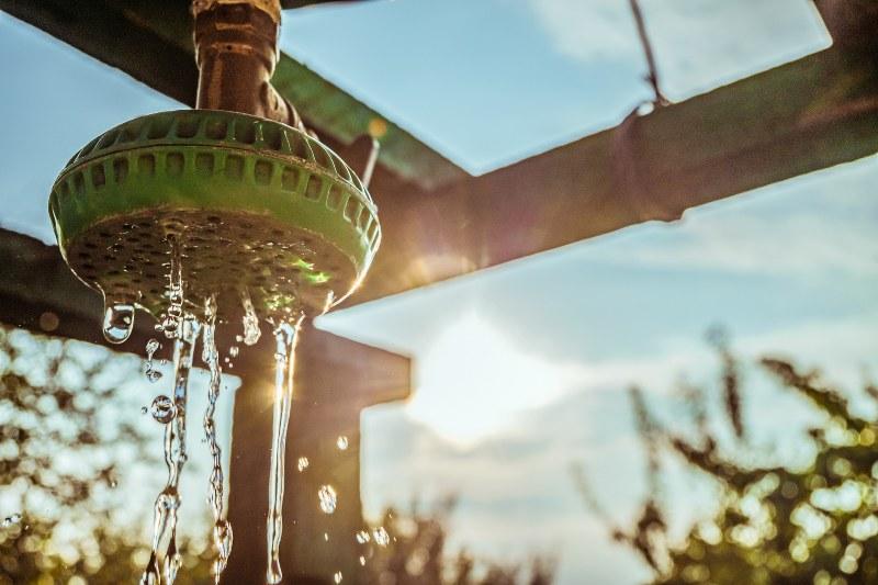 Der Duschkopf einer selbstgebauten Gartendusche im Abendlicht