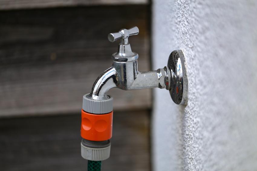 Wasserhahn mit angeschlossenem Gartenschlauch - Wasserzapfstelle