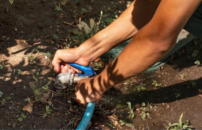 Ein Gärtner fixiert eine Schauchverbindung mit einem Werkzeug Wasserschlauchverbindungen