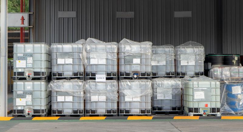 Mehrere IBC-Container stehen vor einem Industrie-Lager Industrie-Container für Flüssigkeiten