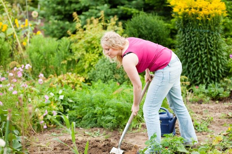 Eine junge Frau gräbt den Garten um 