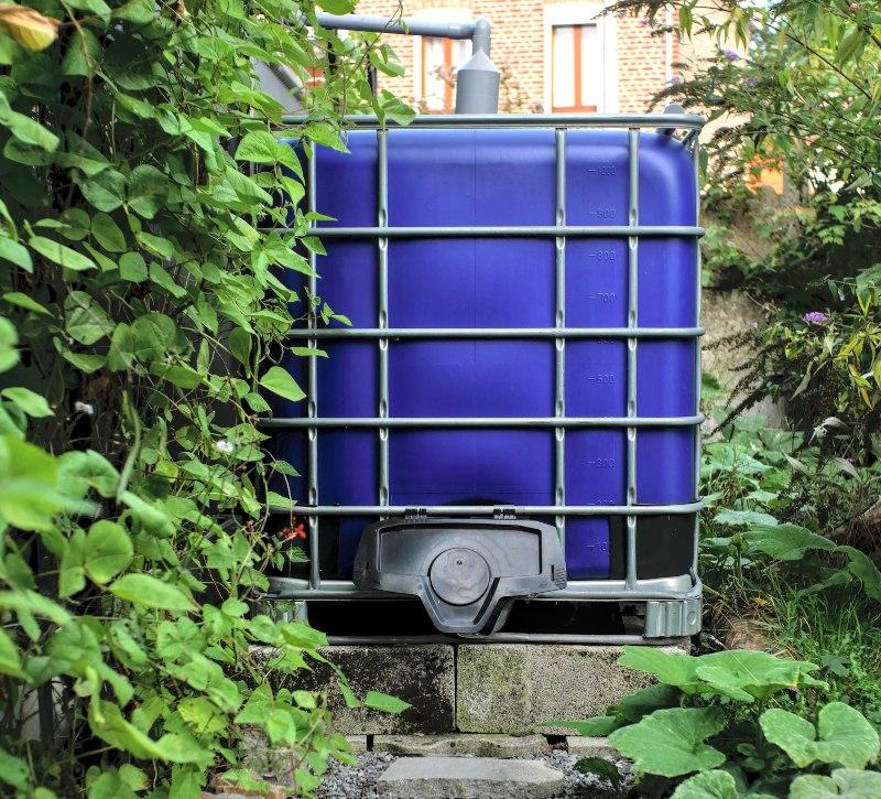 Ein IBC steht erhöht auf einem Fundament aus Steinen IBC Container an ein Fallrohr anschließen