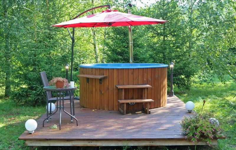 In einem sommerlichen Garten steht ein Hot Tub, der mit Holz verkleidet ist IBC Hot Tub 