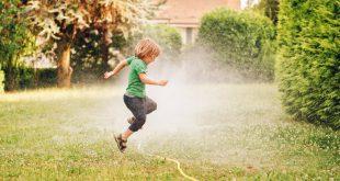 Kind springt über Gartenschlauch - Schlauchregner für Grünflächen