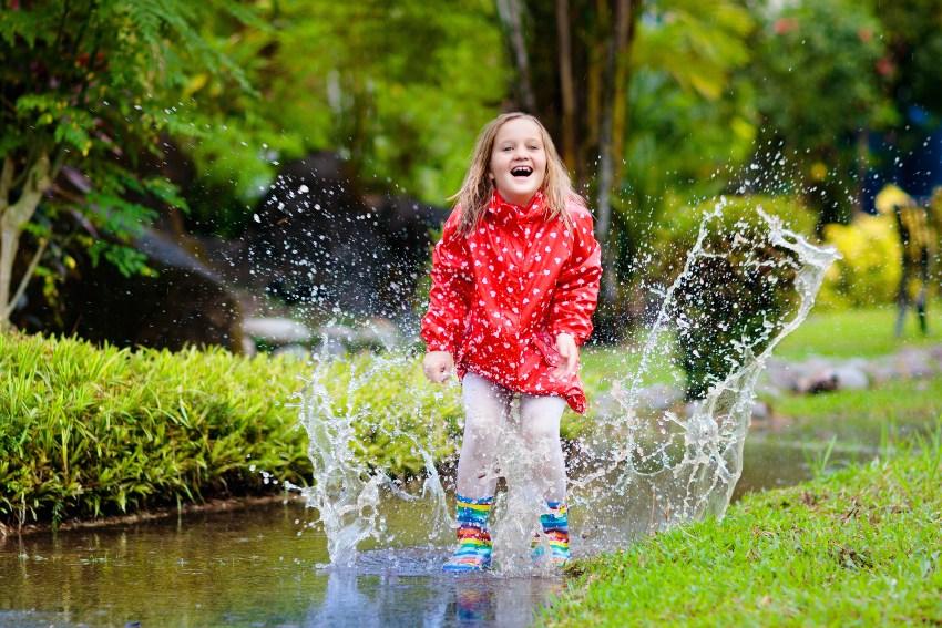 Kind spielt in Pfütze im Garten - Regenwasser ableiten wäre sinnvoller