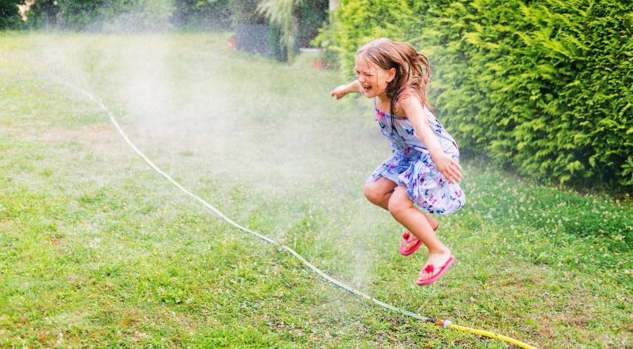 Kind springt über Schlauchregner