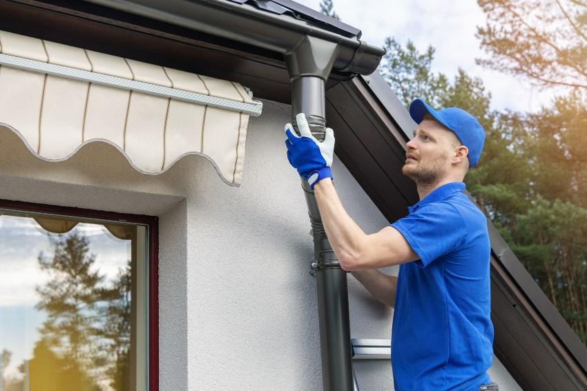 Mann installiert Regenrinn am Haus - Regenwasseraufbereitung