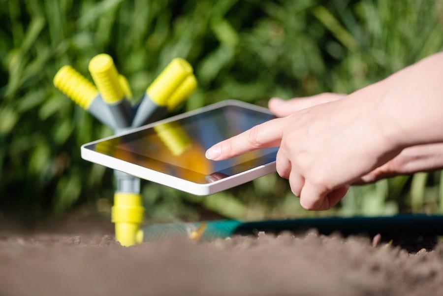 Jemand hat einen Computer für die Gartenbewässerung