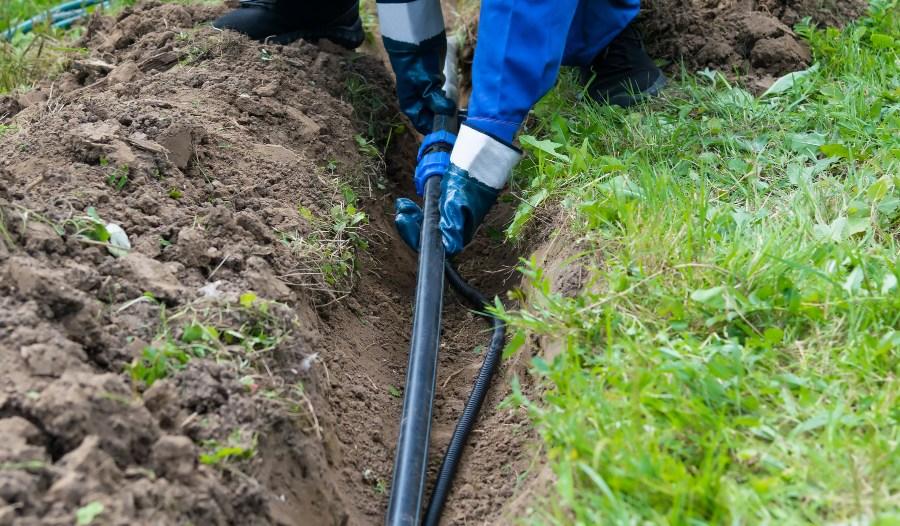 Handwerker verlegt Rohr für Gartenbewässerung