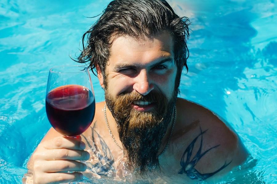 Mann im Pool trinkt Rotwein - Sitzpool selber bauen