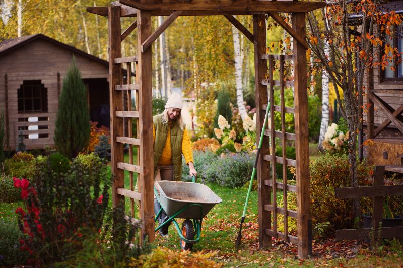 Eine Frau ist im herbstlichen Garten mit Gartenarbeit beschäftigt