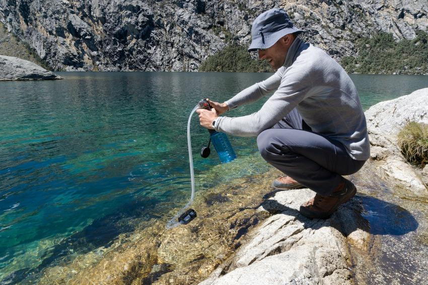 Bergwanderer filtert Bergseewasser