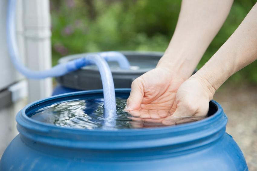 Regentonne, jemand entnimmt etwas Wasser mit deinen Haenden