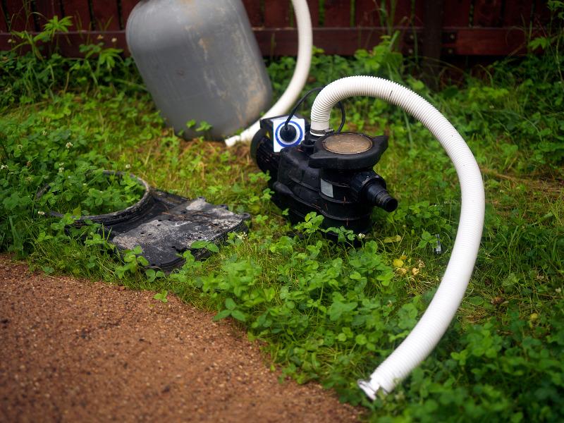 Eine Pumpe mit abgekoppeltem Ansaugschlauch steht vor einem leeren Wassertank