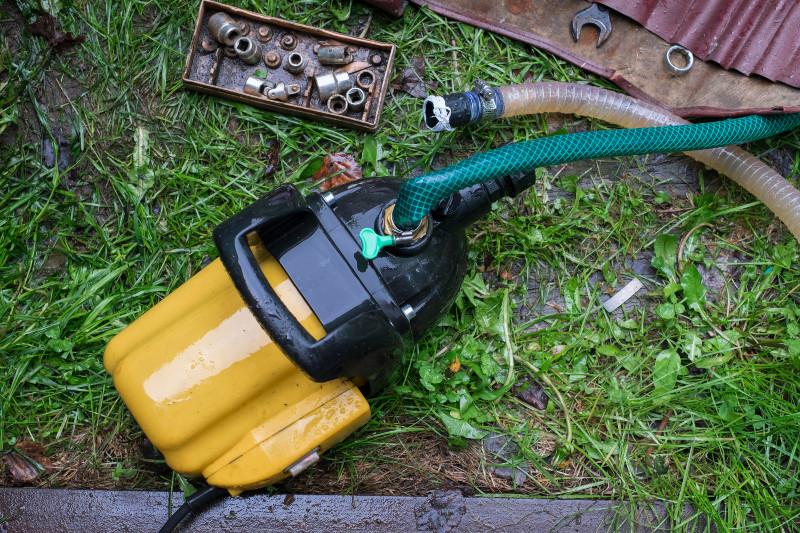 Neben einer Gartenpumpe liegt Werkzeug, einige Schrauben der Pumpe sind bereits gelöst, um sie zu reinigen