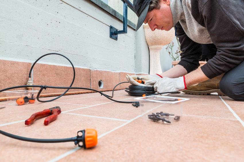 Mann installiert automatisiertes Bewässerungssystem auf einer Terrasse