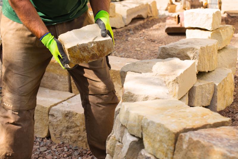 Ein Mann schichtet in einem Kraterbeet Steine zur Hangbefestigung 