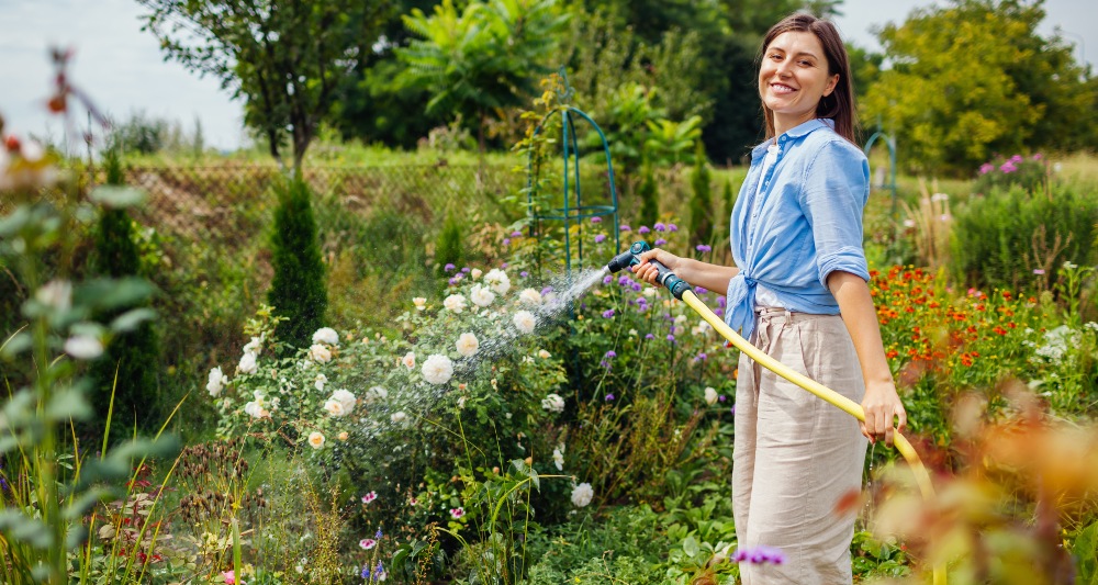 Frau-giesst-Blumen-im-Grten-Welche-Pflanzen-brauchen besonders viel Wasser