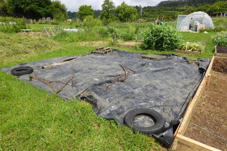 Durch schonende Vorbereitung wird die Fläche für natürliche Prozesse geöffnet und auf die Bepflanzung eingestimmt Gärtner bereitet den Boden im Permakultur-Garten mit Unkrautfolie und recycelten Materialien vor