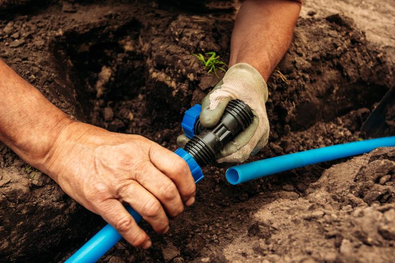 Mann verbindet unterirdische Wasserleitungen für den Garten