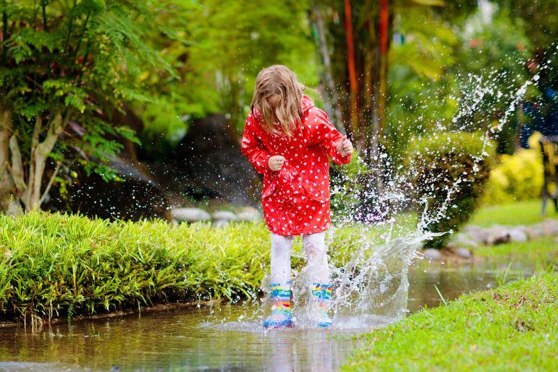 Kind-hüpft-in-einer-Pfütze-im-Garten